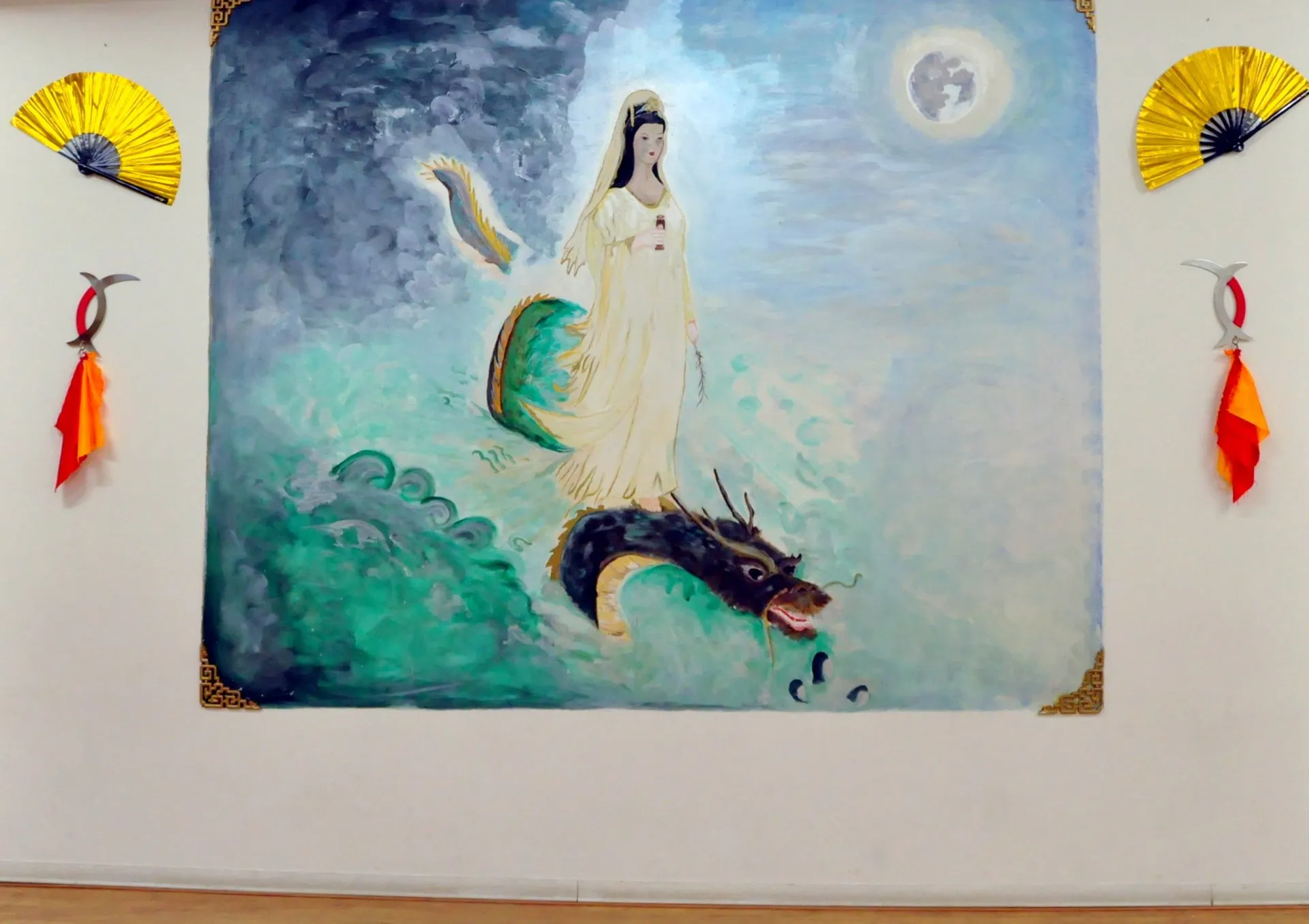Murale con una figura femminile e un drago, con due ventagli appesi, nella sala dell'Accademia